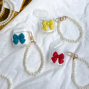 Close-up of clear AirPods TPU cases with 3D bows and white pearl wrist straps