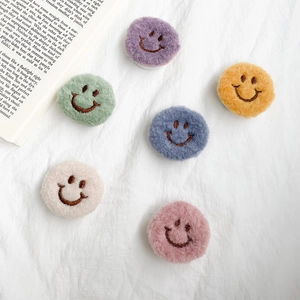Plush smiley face phone socket set in six colors on white fabric background