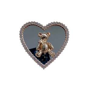 Detail of a golden bear accessory with rhinestone heart mirror and folding phone stand