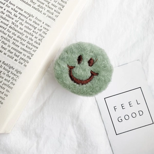 Close-up of a green plush smiley face phone socket on white fabric with an English book