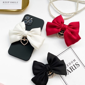 Detail of folding phone socket with large ribbon bow and pearl heart charm accessory