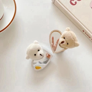 Detail of heart-shaped mini mirror with rhinestone edges and a white plush bear charm