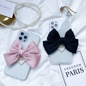 Detail of luxury transparent phone cases with large satin bows and pearl heart pendants