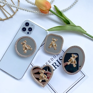 Detailed view of rhinestone-encrusted phone grips with gold bears and mirror surfaces