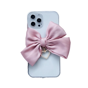 Detail showing transparent iPhone case with pink satin bow and pearl heart pendant charm