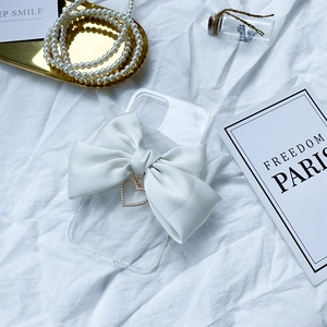 Detail of transparent iPhone case with large white satin bow and heart pearl pendant