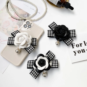 Détail de barrettes camélia avec ruban pied-de-poule et pendentifs en perles