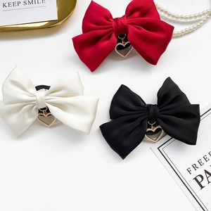 Detail of satin bow hair clips with heart charms in red, white, and black colors