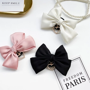 Detailed shot of bow-knot phone grips with heart pendants in pink, black and white colors