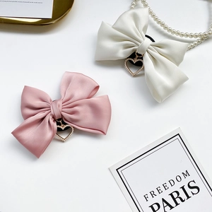 Detailed view of satin bow hair ties with heart pendants and pearl accents