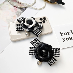 Détail du support de téléphone camélia avec texture cuir et nœud pied-de-poule élégant