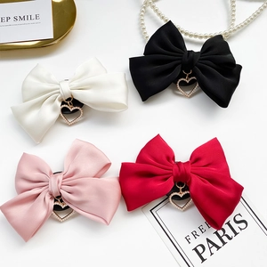 Detailed view of satin bow accessories with pearl heart charms in four colors