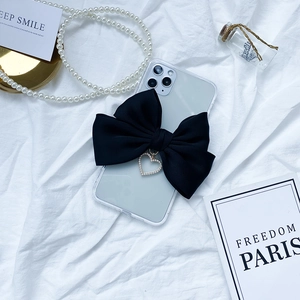 Detail of transparent phone case with large black fabric bow and pearl heart pendant