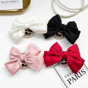 Detail of satin bow phone grips with heart charms in white, black, pink, and red colors