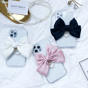 Detailed view of clear phone cases with large satin bows and pearl heart pendants
