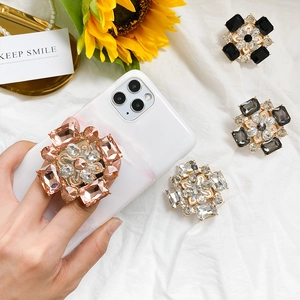 Détail de supports de téléphone en strass colorés posés sur un fond en tissu élégant et chic