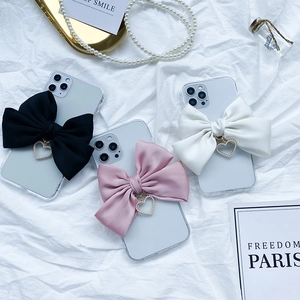 Detailed view of phone cases with satin bows, pearl heart charms in black, pink and white