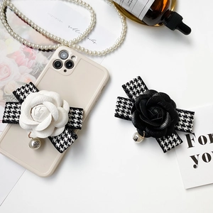 Détail du support de téléphone camélia en cuir avec nœud pied-de-poule et perle
