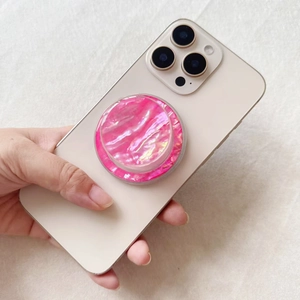 Macro shot of pink mother-of-pearl pattern Magsafe phone grip on white textured fabric