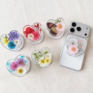 Close-up of six heart-shaped resin phone grips featuring real dried flowers and gold leaf