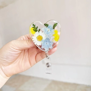 Close-up of heart-shaped resin badge reel with real dried flowers and a rotating clip
