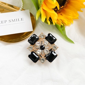 Détail d'une broche florale vintage avec pierres noires sur un fond élégant et raffiné