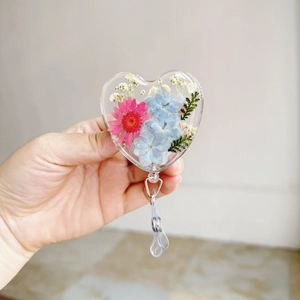 Close-up of heart-shaped badge reel with real dried flowers and retractable clip