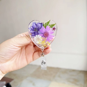 Detail of heart-shaped badge reel featuring real dried flowers in transparent resin