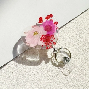 Heart shaped retractable badge reel featuring real dried flowers and a metal clip