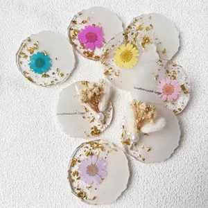 Handmade floral resin coasters with gold foil and dried flowers in irregular wavy shapes
