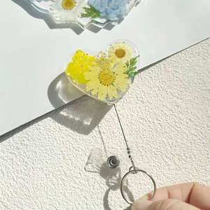 Macro detail of heart-shaped retractable badge holder with real dried flowers and resin