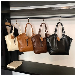Close-up of four stylish tote bags in various colors with cute bear pendants and woven straps