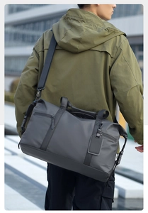 Detail of dark grey travel bag showing waterproof fabric, side pocket, and adjustable strap