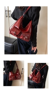 Detail of red glossy shoulder bag featuring dual buckle pockets and adjustable straps