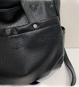 Vue détaillée du cuir noir grainé et d'une boucle en métal argenté sur un sac cabas