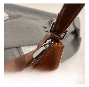 Close-up of high-quality metal zipper and polished hardware on brown patent leather bag