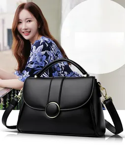 Close-up of black lychee-textured leather handbag with metal magnetic buckle and strap