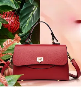 Close-up of red lychee grain leather handbag with gold metal clasp and protective feet