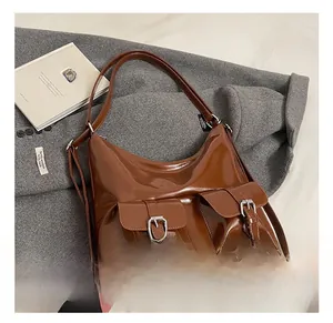 Close-up of brown glossy shoulder bag featuring double front pockets and silver buckles