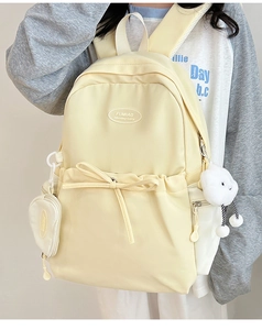 Detail of light yellow nylon backpack with bow decor and cute plush cloud pendant