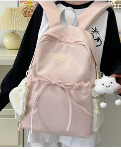 Detailed view of pink school backpack with bow decoration and cute heart-shaped pendant