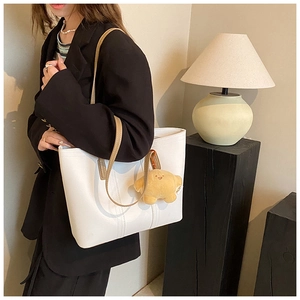 Lifestyle shot of a white minimalist tote bag with thin brown straps and a star charm