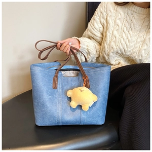 Detail of grey-blue faux leather tote bag with brown handles and yellow star charm