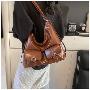 Detail of a brown glossy leather shoulder bag with two vintage metal buckle pockets
