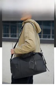 Outdoor shot of a black travel bag with adjustable strap and silver zippers for men