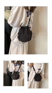 Detail view of black nylon drawstring bucket bag featuring mesh pocket and adjustable strap