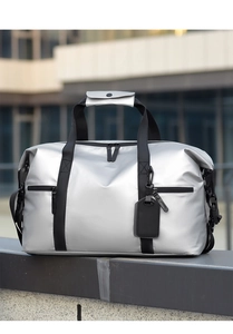 Detail of silver waterproof travel bag with black nylon handles on a stone platform