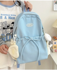 Detail view of water-resistant light blue canvas backpack with heart-shaped charm accessory