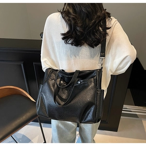 Détail d'un sac cabas noir à texture litchi et bandoulière large amovible