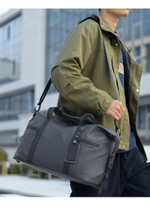 Close-up of matte waterproof black travel bag with dual handles and adjustable shoulder strap